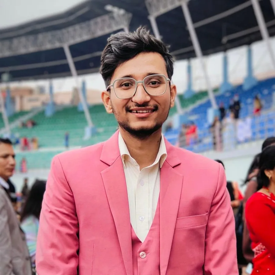 Arun Sapkota in a pink suit, smiling, in a stadium